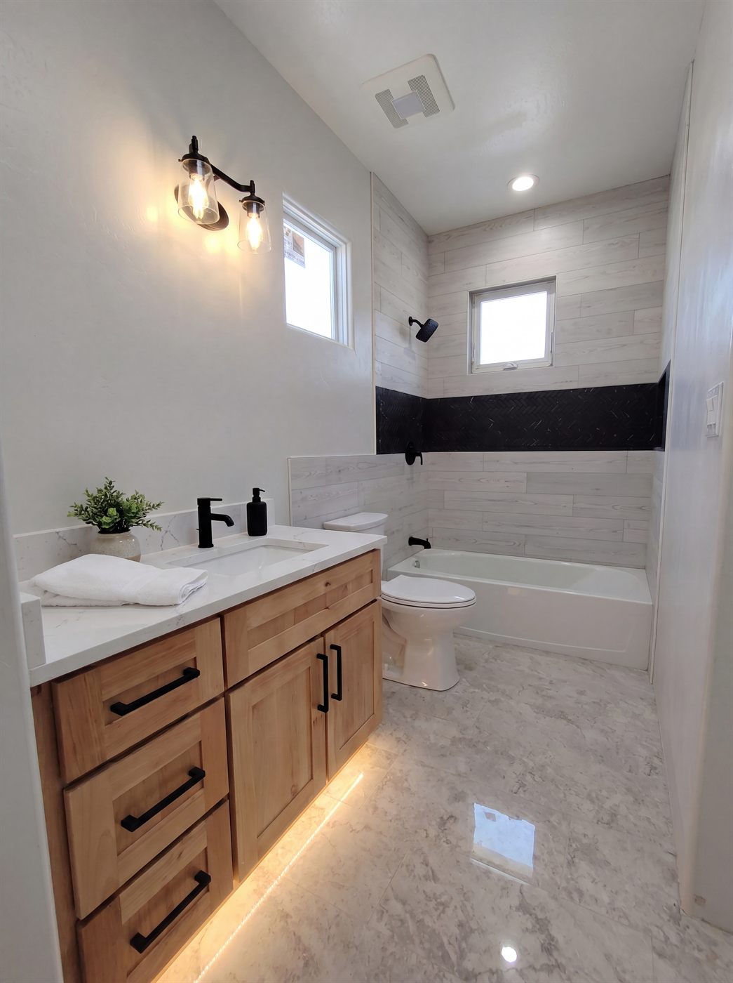 Modern farmhouse full bathroom remodel with maple vanity, quartz countertop and tiled tub surround