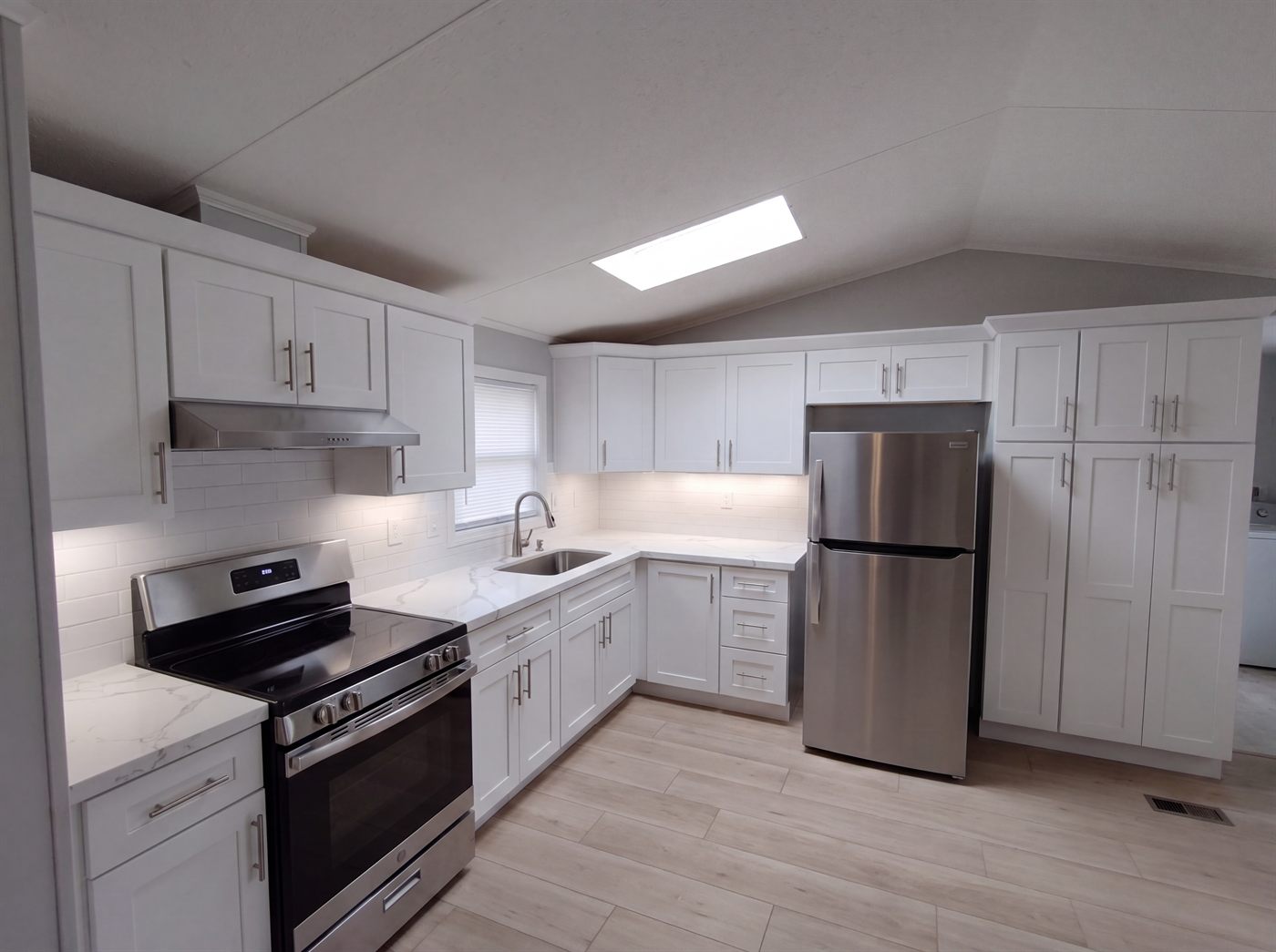 Modern white shaker kitchen remodel with quartz countertops and stainless steel appliances